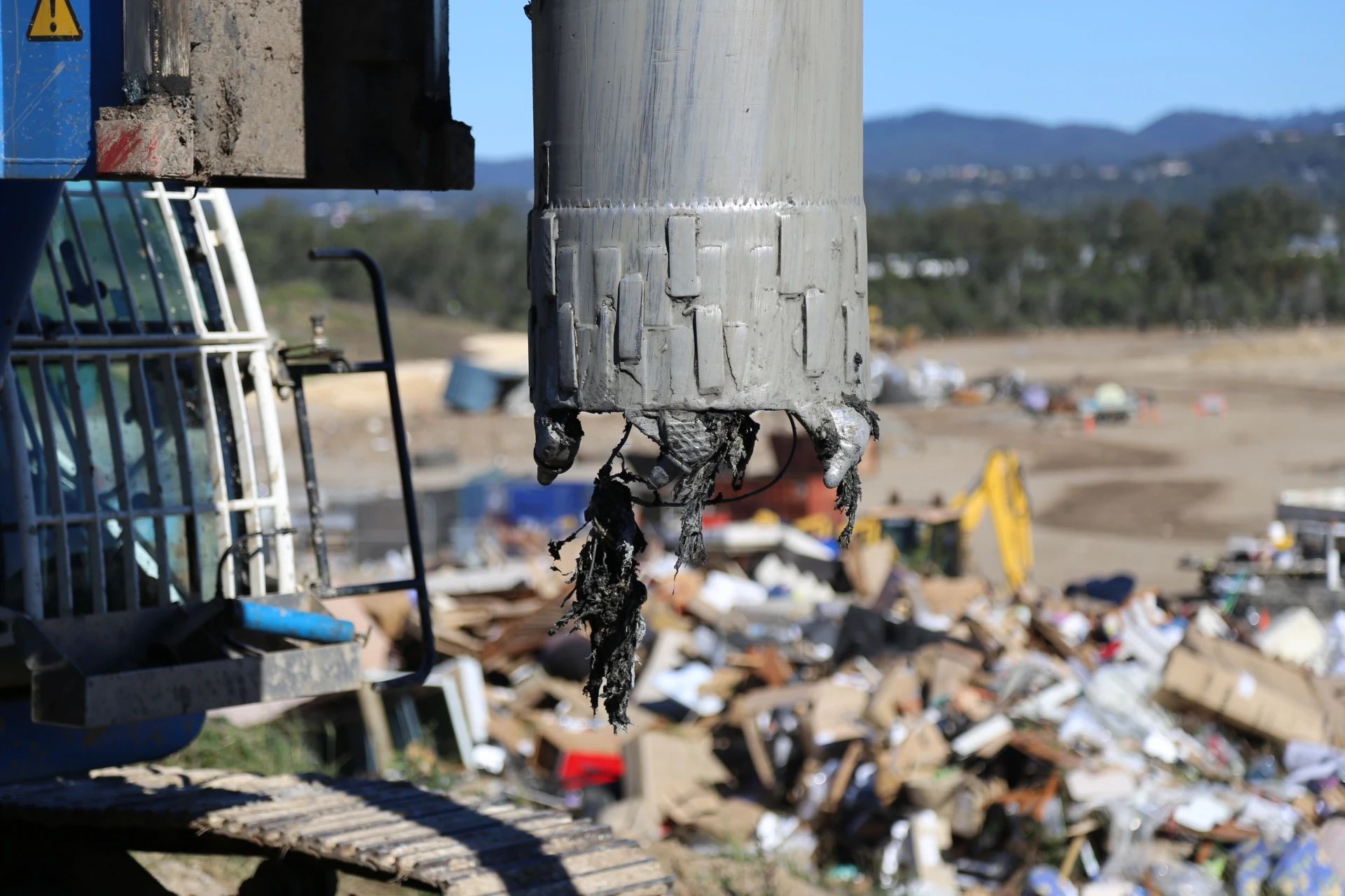 Close-up of drilling tooling working through landfill material