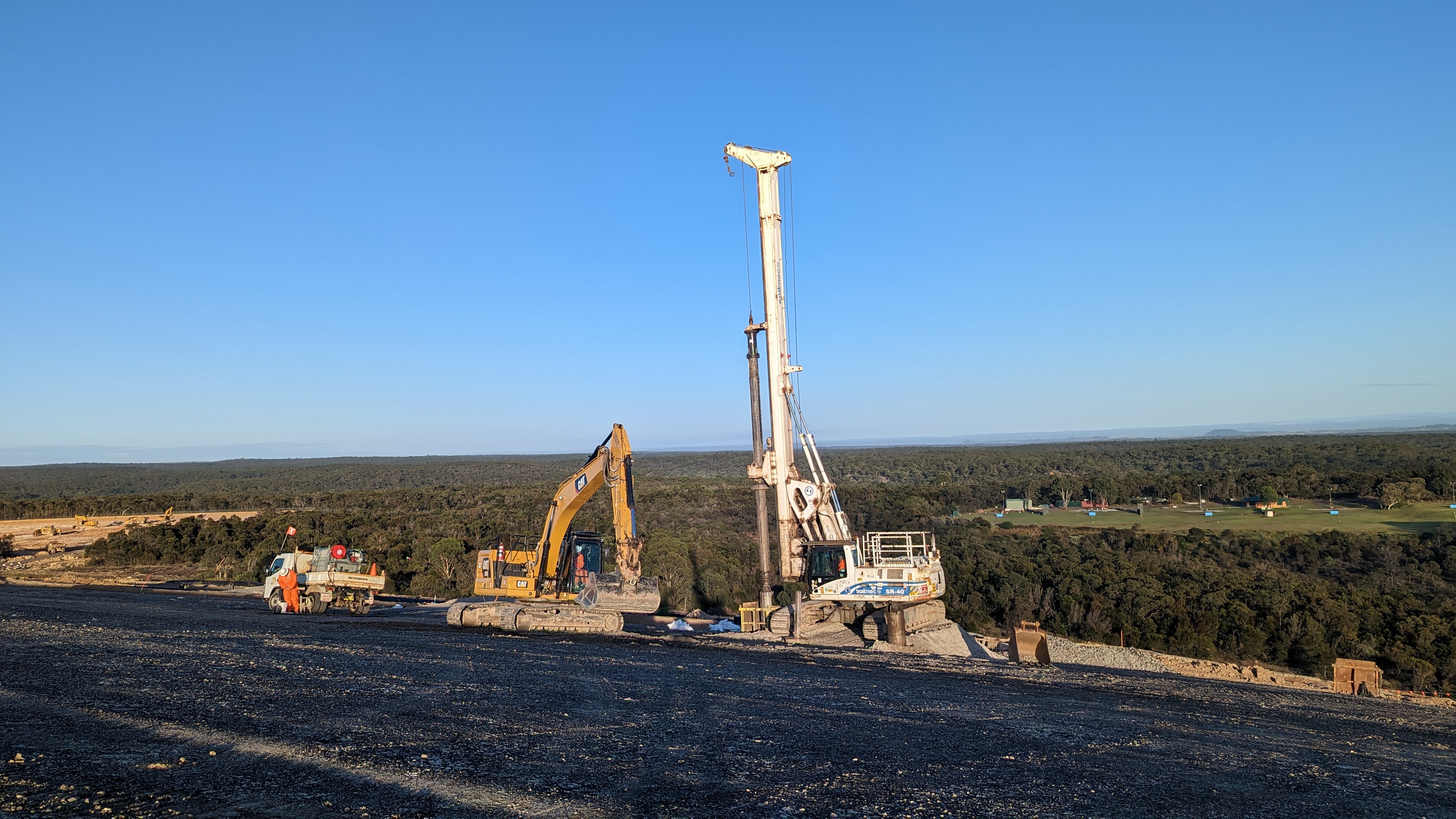 Landfill Drilling rig and excavator working on site overlooking bushland